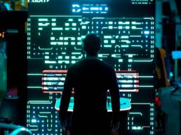 The back view of a man looking up at a large screen presenting an Arcade game as part of GOTO Events - Arcade Games.