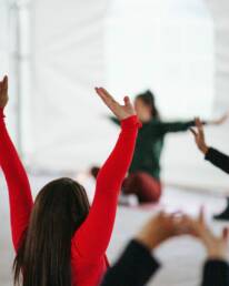 A lady with her arms stretched in the air, copying instructions from a yoga instructor as part of GOTO Creates Company Away Days.