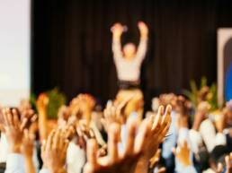 A blurred image of hands being raised as part of a GOTO Creates Conference Energiser