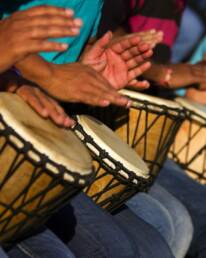 People sitting in a line banging bongos as part of a GOTO Creates conference energiser.