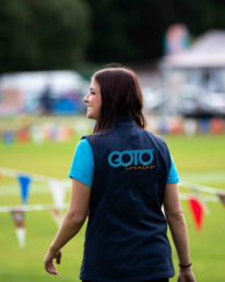 A GOTO Creates team member is smiling and walking through a field with lots of bunting.