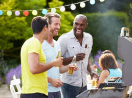 A group of men cooking on a barbeque, laughing as part of GOTO Creates Summer BBQ.