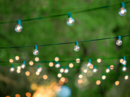 Hanging decorative christmas lights for a backyard party as part of GOTO Creates summer party.