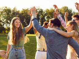 A bunch of happy young friends all together celebrating in a field, following GOTO Creates Team Fun