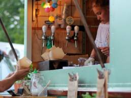 Food being served from a GOTO Creates drink van, which is painted light blue and decorated with small lantern lights.