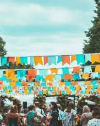 Orange and blue bunting hanging over a group of people at a GOTO Creates summer party.