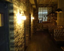 A dimly lit room with brick walls and leather booths.