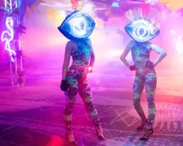 dancers in eye costumes and neon signs