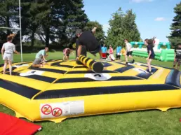 adult and children playing on yellow inflatable at corporate event